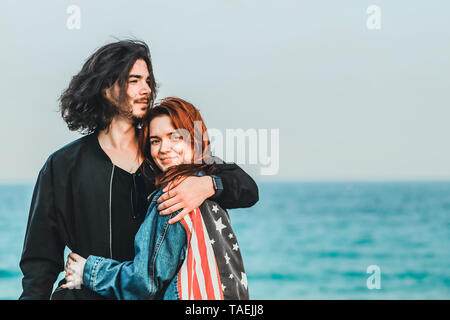 Happy young couple sur la mer par une chaude journée de printemps. Bel homme étreintes doucement sa belle Rousse sweetheart.