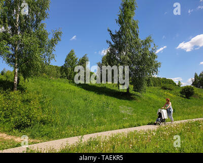 Mitino parc paysager. Belle journée chaude en Mai ( Mitino - banlieue de Moscou ). femme fait rouler la poussette Banque D'Images