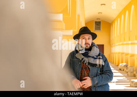 Portrait d'un beau jeune homme élégant avec un foulard à l'extérieur. Un homme portant un foulard, un chapeau et une jaket à la confiance à l'appareil photo. Banque D'Images