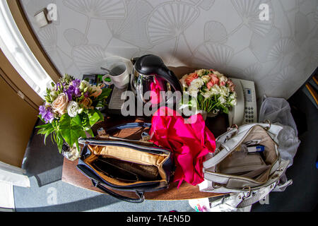 Les choses d'ouvrir lady sac. Théière, tasse à café, téléphone, foulard rouge, sacs, bouquets de fleurs et autres produits de beauté et des accessoires sur table de noce Banque D'Images