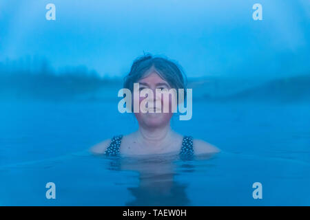 Karen Rentz trempage dans le Secret Lagoon, une des sources chaudes naturelles dans la région de Fludir, Islande Banque D'Images