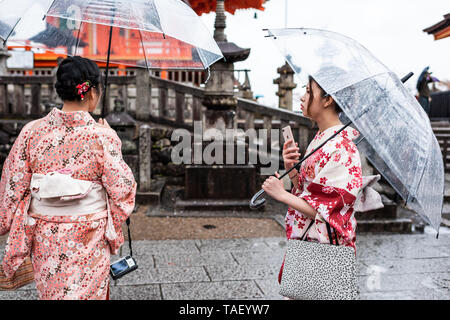 Kyoto, Japon - 9 Avril 2019 : deux femmes avec kimono et parasols à rester debout au cours de jour de pluie dans le temple Kiyomizu-dera Banque D'Images