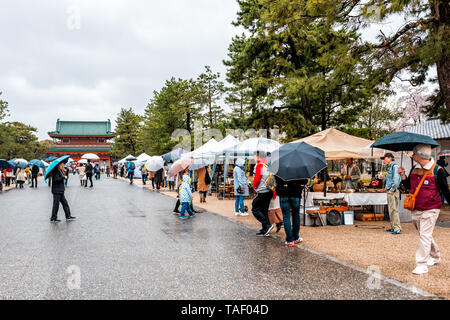 Kyoto, Japon - 10 Avril 2019 : Les gens avec des parasols au cours de jour de pluie marcher dans des marchés dans le parc d'Okazaki avec vue sur le Sanctuaire Heian Banque D'Images