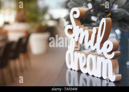 Gros plan du sourire et rêve mots en bois sur une surface de verre sur la table de fête, selective focus Banque D'Images