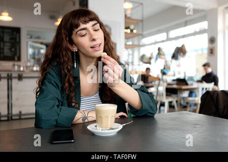 Jeune femme avec milky coffee assis à table dans un café Banque D'Images