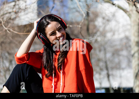 Jeune danseur contemporain porter du rouge sweat-shirt, assis et écouter de la musique Banque D'Images
