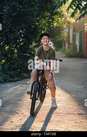 Portrait of smiling boy with vélo BMX sur route Banque D'Images