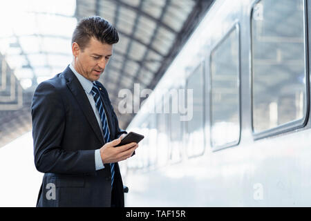 Businessman using cell phone sur la plate-forme Banque D'Images