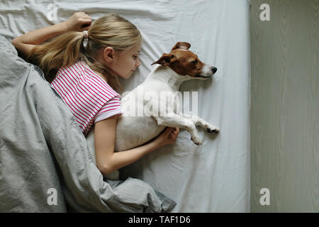 Fille blonde allongée sur le lit avec son chien dormir, vue d'en haut Banque D'Images