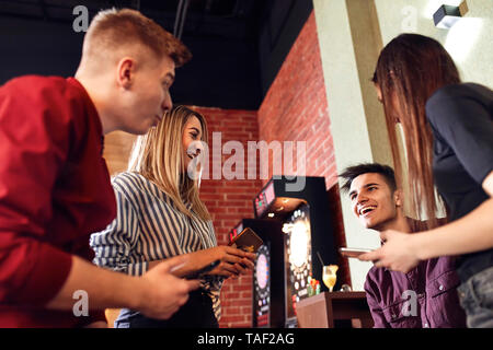 Happy friends avec les smartphones la socialisation dans un bar Banque D'Images