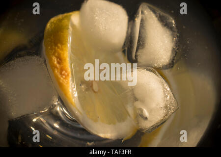 Une photo en gros plan de cubes de glace et un morceau de citron dans un verre d'eau Banque D'Images