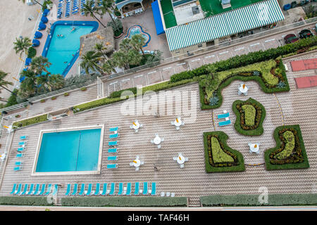 Vue aérienne de deux piscines sur des propriétés voisines par la plage en Floride du Sud. Banque D'Images