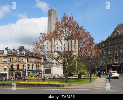 Les personnes bénéficiant du soleil un jour de printemps au cénotaphe dans le centre de Harrogate, Yorkshire, Angleterre, Royaume-Uni. Banque D'Images