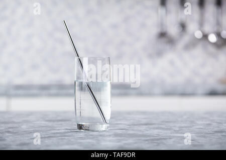 Close-up of Metal paille dans du verre transparent de l'eau sur le comptoir de la cuisine Banque D'Images