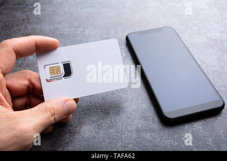 De l'homme près de la carte SIM du smartphone sur le fond en béton Banque D'Images