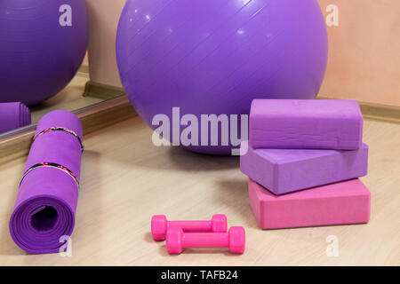 Outils de remise en forme - ball, rose et violet cubes et les haltères, tapis pourpre, concept sportif,photo horizontale Banque D'Images