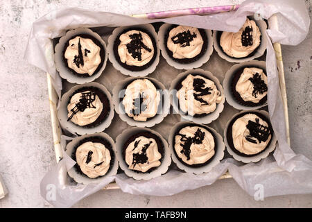 Belle crème au chocolat cupcakes couvert dans une case blanche attachés avec une corde sur un fond en béton Banque D'Images