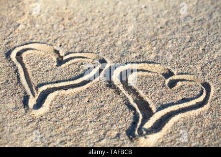 Close-up de deux Cœurs dessinés à la main sur du sable à la plage Banque D'Images