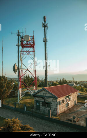 Les tours de télécommunication avec les antennes d'une station de base transceiver, sur le coucher du soleil à Guarda. Une ville médiévale à l'est du Portugal. Banque D'Images