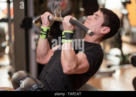 Guy gaies les muscles dorsaux de formation en prenant en charge et de les mettre vers le bas. L'exercice de force concept . Banque D'Images