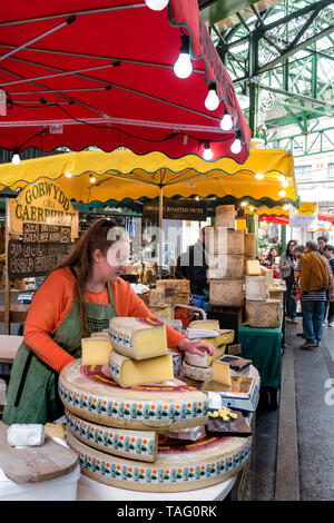 Étals de fromage du marché de l'arrondissement avec parasols rouges et jaunes, avec dégustation de caerphilly au Borough Market Southwark London SE1 Banque D'Images