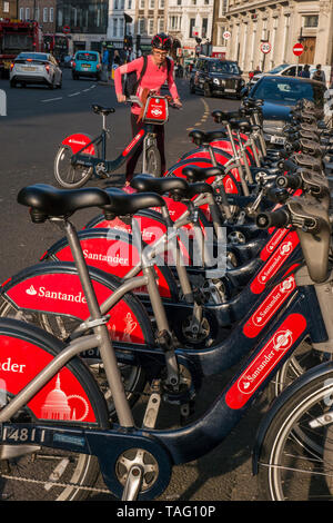 TFL Santander sponsorisé Londres rouge location de vélos à Southwark Street avec une cycliste femme portant un casque de sécurité sur le point de commencer sa location de vélo à partir de la station d'accueil du terminal de vélo. Transport pour Londres Southwark Londres Royaume-Uni Banque D'Images