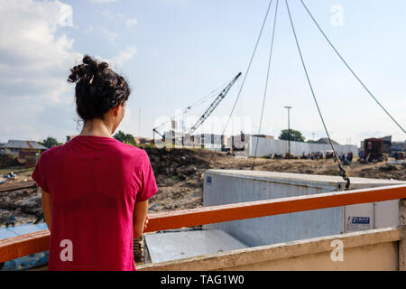 Femme à la façon dont les conteneurs sont chargés sur un ferry au Puerto Henry sur l'Amazone à Iquitos, Pérou, département de Loreto Banque D'Images