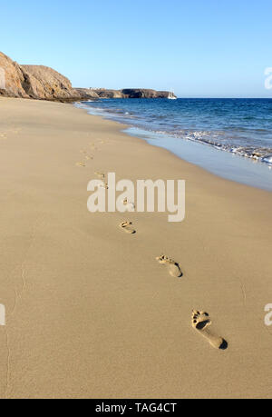 Une piste d'empreintes de pieds adultes sont laissés sur la rive dans le sable doré sur la plage de Papagayo, Lanzarote. La plage est baignée de soleil du soir chaud Banque D'Images