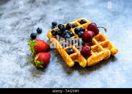 Close-up d'une gaufre avec les bleuets et les fraises avec de délicieux aspect, isolé sur fond abstrait avec copie espace pour le texte. Banque D'Images