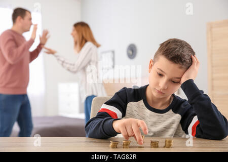 Triste petit garçon avec des pièces de monnaie et ses parents se disputer à la maison. Concept de soutien de l'enfant Banque D'Images