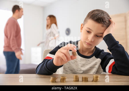 Triste petit garçon avec des pièces de monnaie et ses parents se disputer à la maison. Concept de soutien de l'enfant Banque D'Images