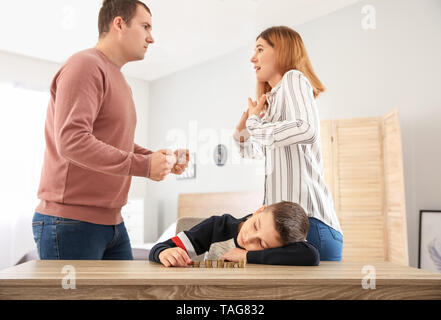 Triste petit garçon avec des pièces de monnaie et ses parents se disputer à la maison. Concept de soutien de l'enfant Banque D'Images