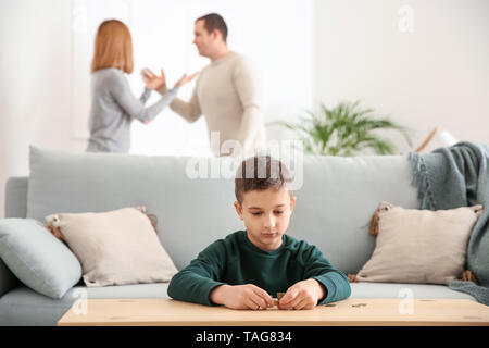 Triste petit garçon avec des pièces de monnaie et ses parents se disputer à la maison. Concept de soutien de l'enfant Banque D'Images