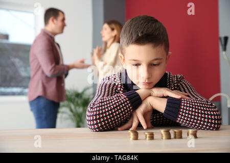 Triste petit garçon avec des pièces de monnaie et ses parents se disputer à la maison. Concept de soutien de l'enfant Banque D'Images