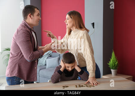 Triste petit garçon avec des pièces de monnaie et ses parents se disputer à la maison. Concept de soutien de l'enfant Banque D'Images