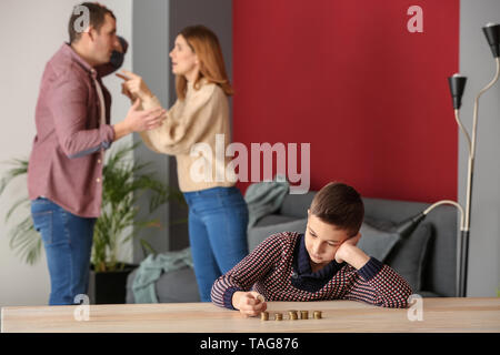 Triste petit garçon avec des pièces de monnaie et ses parents se disputer à la maison. Concept de soutien de l'enfant Banque D'Images