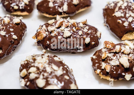 Le Français Madeleines trempées dans le chocolat au lait avec noisettes concassées parsemées sur le dessus, assis sur un arrière-plan en marbre blanc Banque D'Images