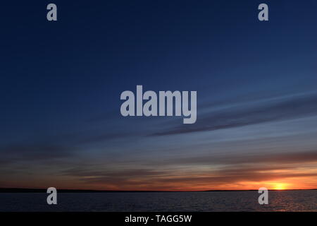 Ciel crépusculaire à la lueur du coucher de soleil sur l'horizon au-dessus de l'eau du lac Banque D'Images