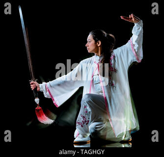 Une femme chinoise Tai Chi Chuan partacticing Tadjiquan posture studio shot isolé sur fond noir avec effet light painting Banque D'Images