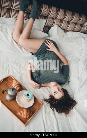 Belle jeune fille au lit avec petit déjeuner sur plateau en bois dans la chambre d'hôtel. Bonjour. Banque D'Images