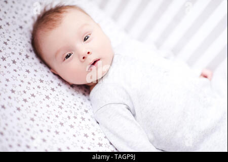 Mignon bébé garçon couché dans le lit libre. En regardant la caméra. Chidlhood. Banque D'Images