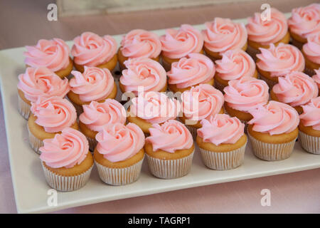 Peu de vanille cupcakes avec glaçage rose dans une rangée Banque D'Images