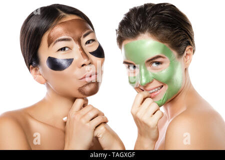 Deux belles filles avec des masques peel-off sur leurs visages. Isolé sur fond blanc Banque D'Images