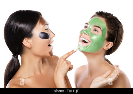 Deux belles filles avec des masques peel-off sur leurs visages. Isolé sur fond blanc Banque D'Images