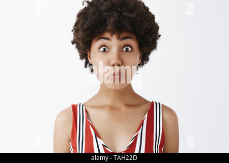 Je suis muet comme le poisson pas de secret d'échapper. Portrait de enjoué et drôle bon-à la young african american avec cheveux bouclés tacaud, holding Banque D'Images