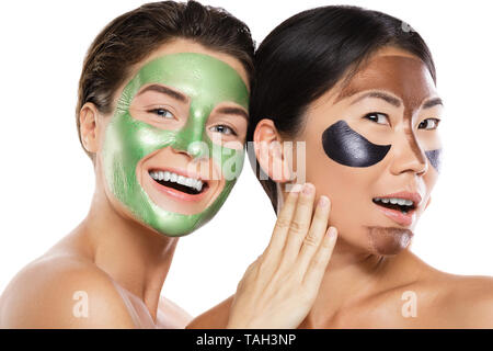 Deux belles filles avec des masques peel-off sur leurs visages. Isolé sur fond blanc Banque D'Images