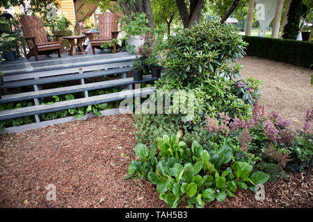 Des chaises en bois sur un podium en bois dans le jardin parmi les plantes Banque D'Images