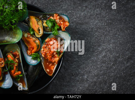 La cuisson des moules fruits de mer crustacés avec plaque de moule zébrée verte ocean shell dîner gastronomique préparé avec des herbes et épices sauce chili Banque D'Images