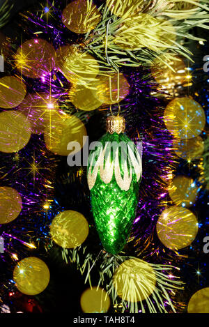 Babiole décorative de Noël vert est sur un arbre de Noël entouré de guirlandes et de lumières de fête Banque D'Images