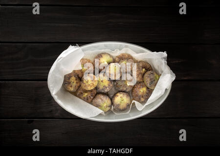 Vue de dessus de figues fraîches dans la caisse sur la table en bois. La photographie alimentaire sombre Banque D'Images